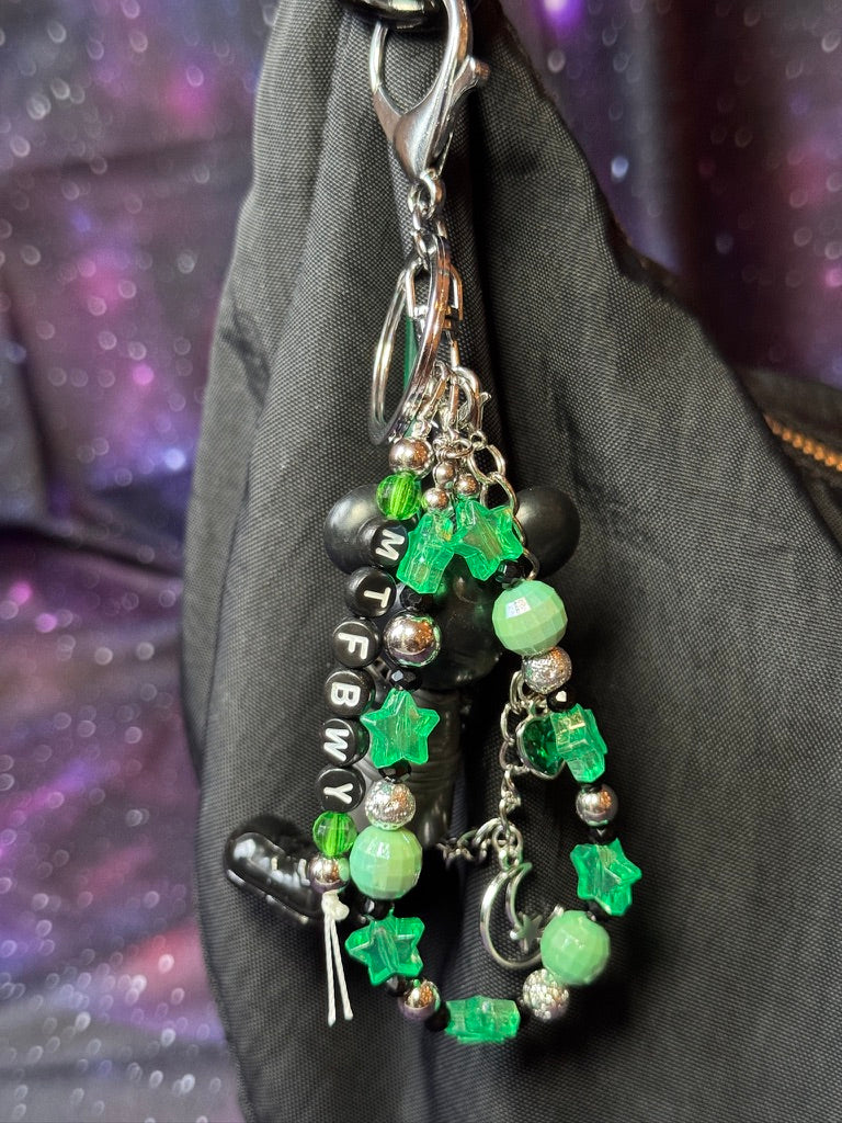 Mickey Mouse figure dressed in black outfit styled like Luke Skywalker from Return of the Jedi. Figure is attached to a silver keychain with green, silver and black charms and beads. MTFBWY letter charm. 
