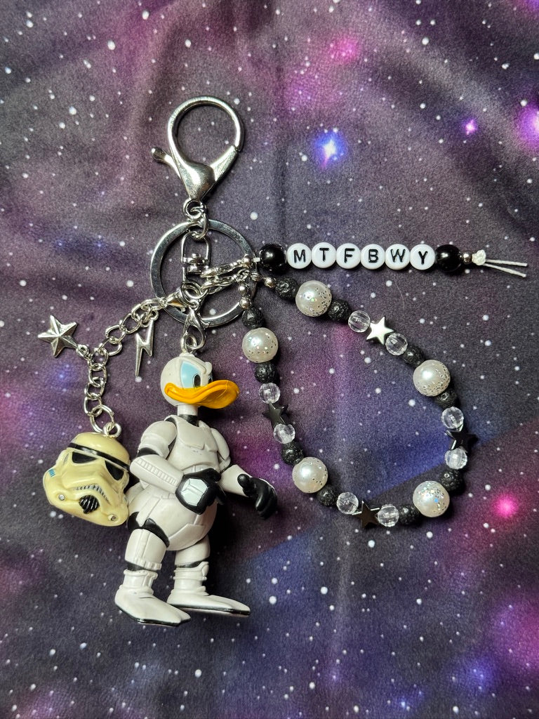 Donald Duck styled as a Stormtrooper from Star Wars figure. Attached to a silver keychain with coordinating beads in a black, silver and white color scheme. MTFBWY bead charm. Figure is set against a purple background. 